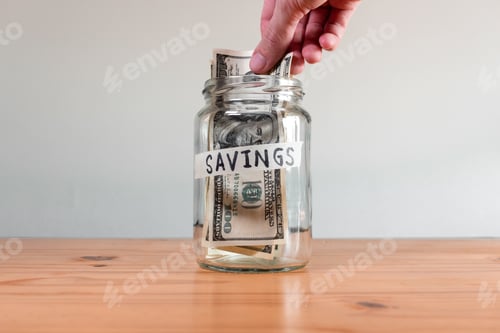 Preview: Savings Jar with Money on Wood Table