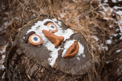 Preview: stump of big tree with decorative elements if shape of human face in winter forest