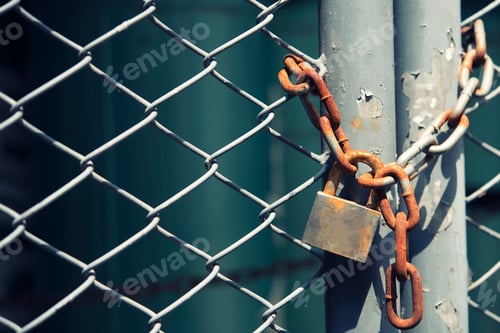 Preview: Grunge old lock in barbed wire fence with sunlight. Safety concept.