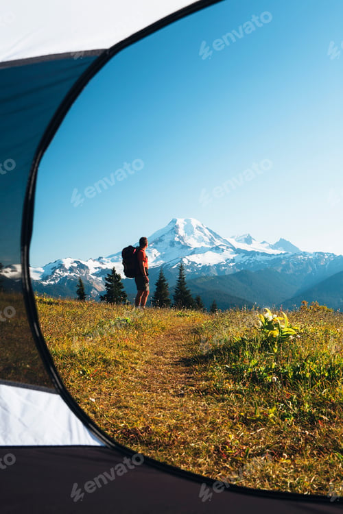 Preview: View from inside a camping tent of a man hiking with Mount Baker in the distance.
