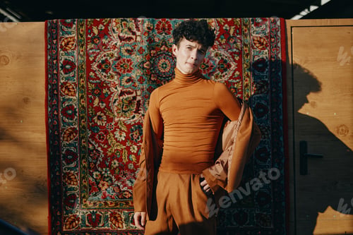 Preview: Fashion model in a stylish brown outfit posing against a vibrant patterned backdrop