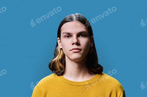 Preview: Headshot portrait of serious teenage guy on blue studio background