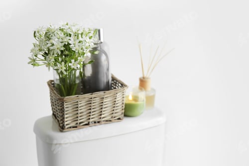 Preview: Decor elements on toilet tank near white wall, space for text. Bathroom interior