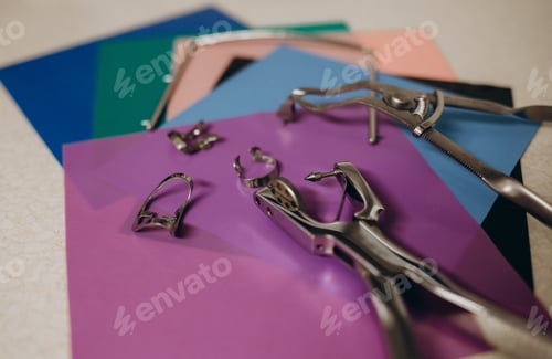 Preview: Tools for installing the cofferdam rubberdam and clamp lying on the table. Dental tools.