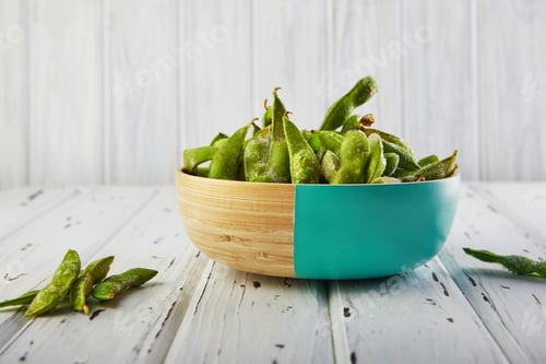Preview: Frozen Edamame or soybeans in a wooden plate on a white wooden background