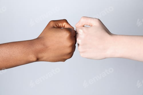 Preview: Stop racism. People of different skin colors bumping fists on light grey background, closeup