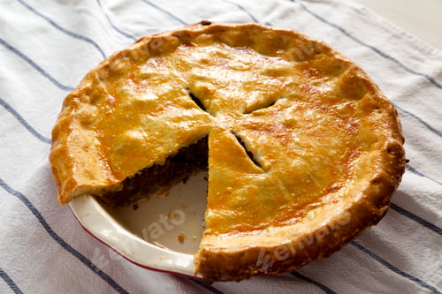 Preview: Tasty Homemade Canadian Tourtiere Meat Pie on a white plate , side view. Closeup.