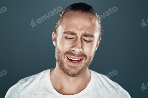 Preview: Hysteria. Frustrated young man making a face while standing against grey background