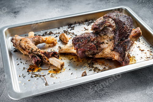 Preview: Roasted lamb mutton whole leg in a baking dish. White background. Top view