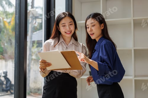 Preview: Asian colleagues collaborating on project, discussing business document