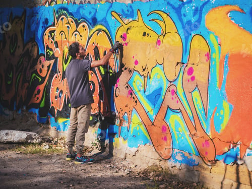 Preview: Creative art - teenage boy painting colorful abstract ornament graffiti on street wall with aerosol
