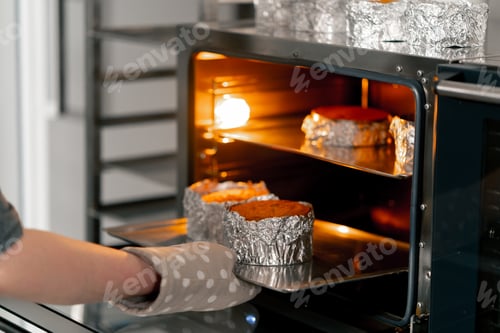 Preview: close up In a professional kitchen a baker takes out ready-made biscuits from the oven