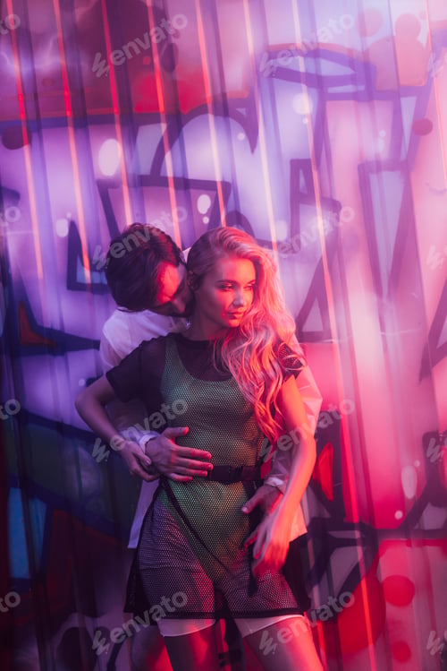 Preview: attractive and blonde woman hugging with handsome man in night club