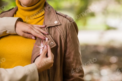 Preview: Daughter pinning breast cancer awareness ribbon on mother