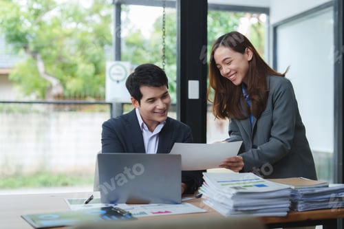 Preview: Business people working together on a project using laptop and documents