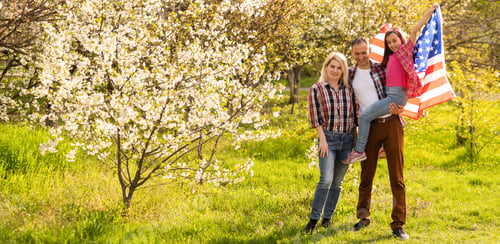 Preview: happy family with the flag of america USA at sunset outdoors
