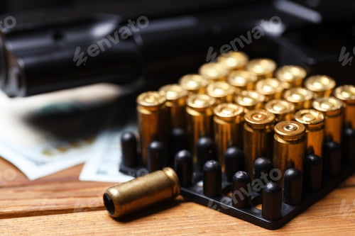 Preview: Cartridges, gun and dollars on wooden table, closeup