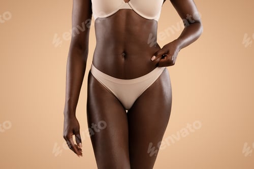 Preview: Unrecognizable black woman in underwear showing excessive fat on belly