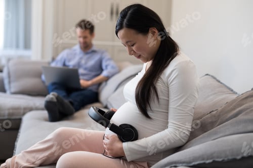 Preview: Pregnant woman placing headphones on her stomach