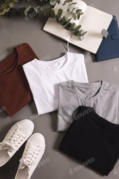 Preview: Multi coloured t shirts, shoes and notebook with copy space on grey floor background