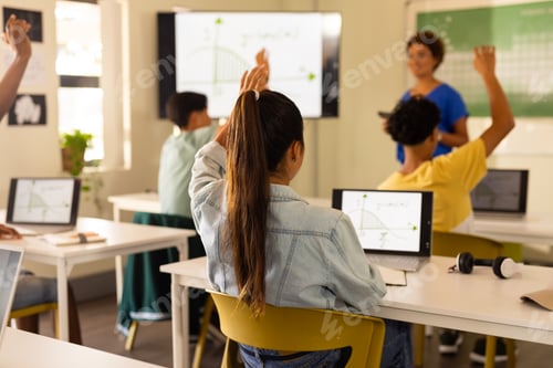Preview: In high school, students raising hands and using laptops during classroom lesson