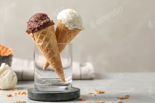Aperçu: Tasty ice cream scoops in waffle cones on grey marble table, closeup. Space for text