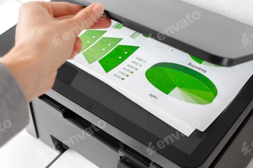 Preview: Hand placing paper in a black printer at a workspace for document printing