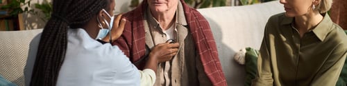 Preview: Senior Man Receiving Medical Checkup from Black Woman Nurse at Home