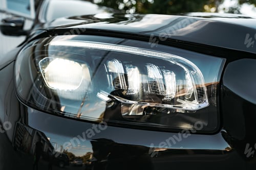 Preview: Modern car headlight of a black luxury car close up