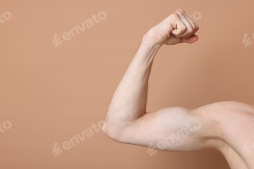 Preview: Man showing his bicep on beige background, closeup. Space for text