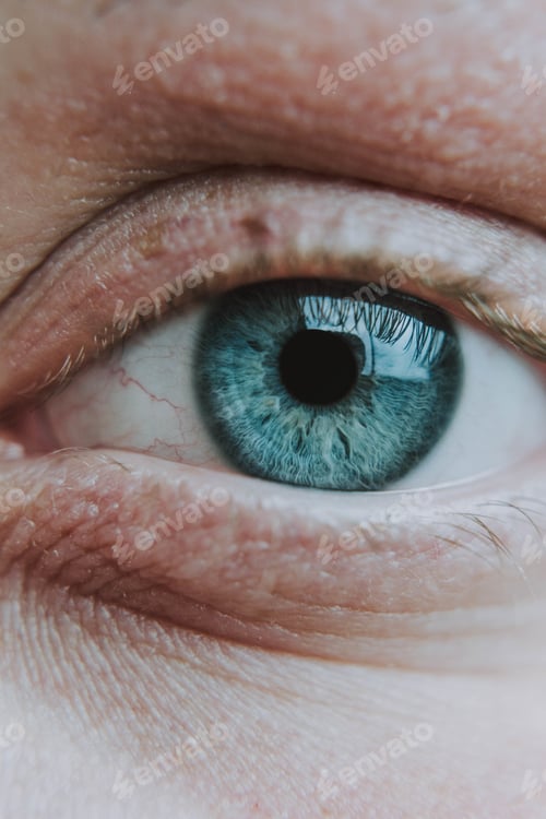 Preview: Vertical closeup shot of an elderly human's light blue eye