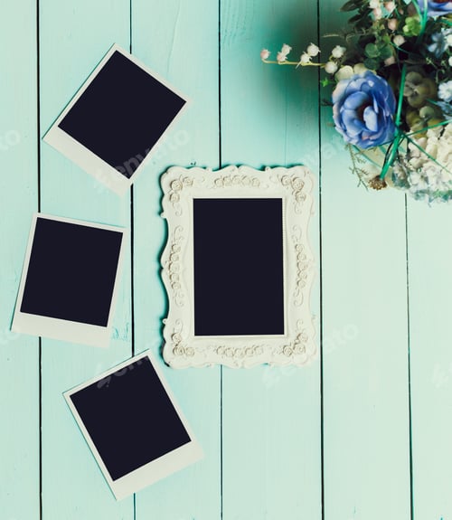 Preview: Unique photo frame and blank pictures on vintage wooden surface with flowers