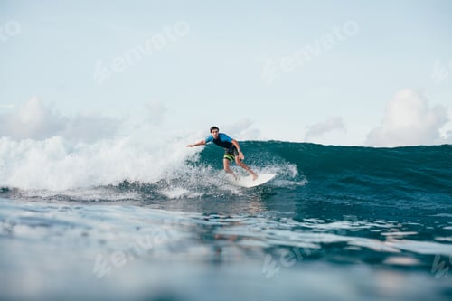 Preview: young man in wetsuit riding waves on surfboard on sunny day