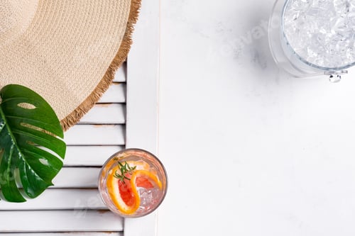Preview: Cold summer drink in a glass with slice of grapefruit and ice cubes and Wide-brimmed hat and green