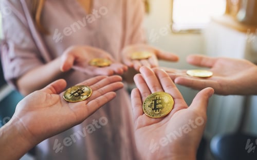 Preview: Closeup image of a group of people holding a golden color bitcoin in hands