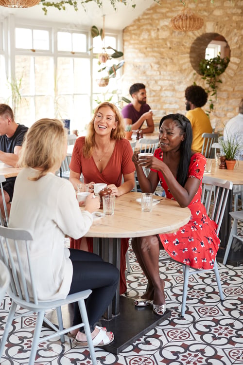 Preview: Three female friends talking over brunch at a cafe, vertical