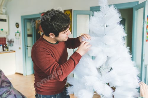 Preview: Young couple at home decorating xmas tree