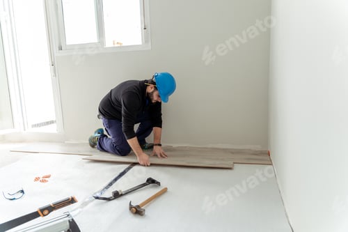 Preview: Man worker assembling laminate flooring.