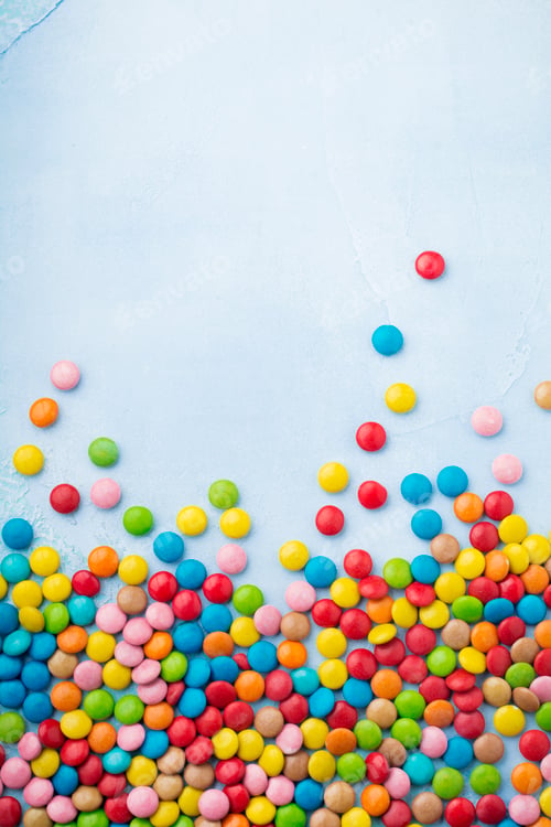 Preview: Chocolate round candy in a multicolored sugar glaze on light blue background. Selective focus. Top v