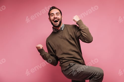 Preview: Happy man celebrates victory and smiles on pink background .