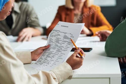 Preview: Selective focus on hands of Muslim female student with grammar test