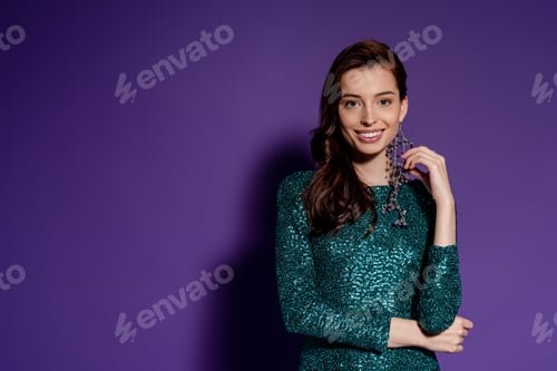 Preview: happy young woman in party dress standing on purple
