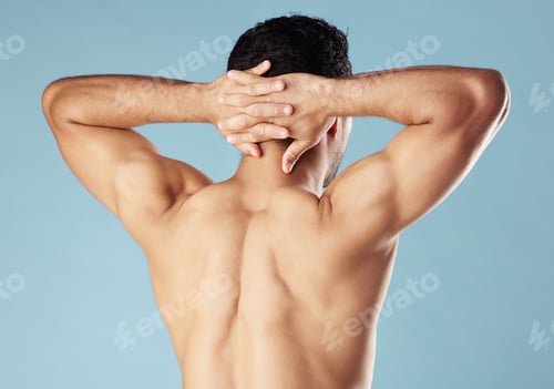 Preview: Rearview young mixed race man standing shirtless in studio isolated against a blue background. Unre