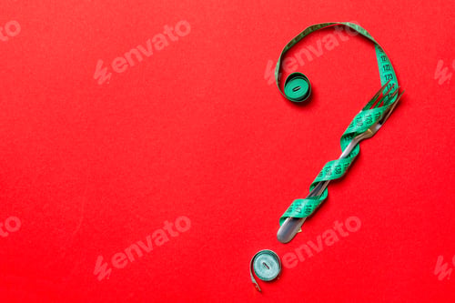Preview: Top view of fork and measure tape in form of question mark on red background.
