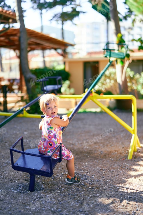 Preview: Little girl sits on a teeter-totter with her head turned back