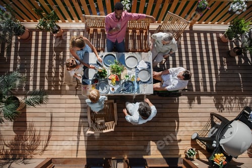 Preview: Top view of 3 generations family eating at barbecue party dinner on patio, people sitting at table