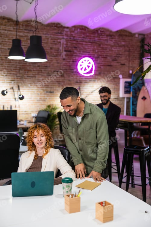 Preview: Multi ethnic team collaborating on laptop in modern office
