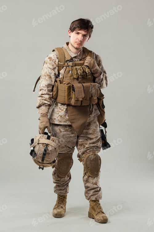 Preview: Person in military uniform holding helmet and standing in studio setting with neutral background