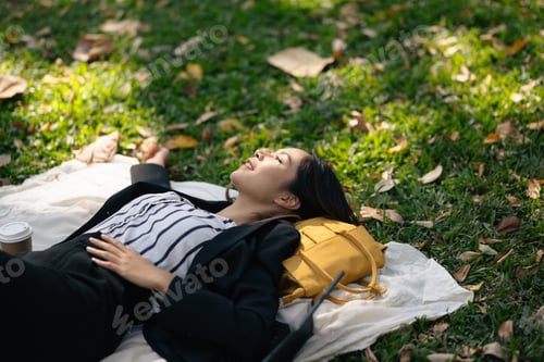 Preview: Happy businesswoman relaxing and breathing fresh air, lying on grass in the park