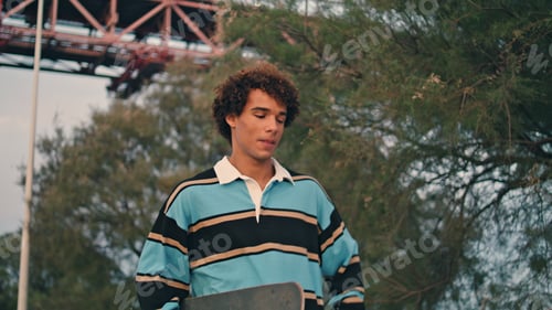 Preview: Positive hipster calling cellphone evening city closeup. Man walking skateboard